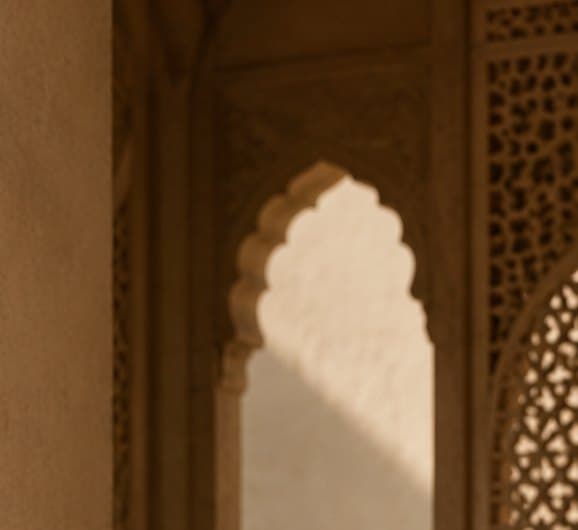 Afternoon light falling through a carved sandstone arch onto a plaster wall