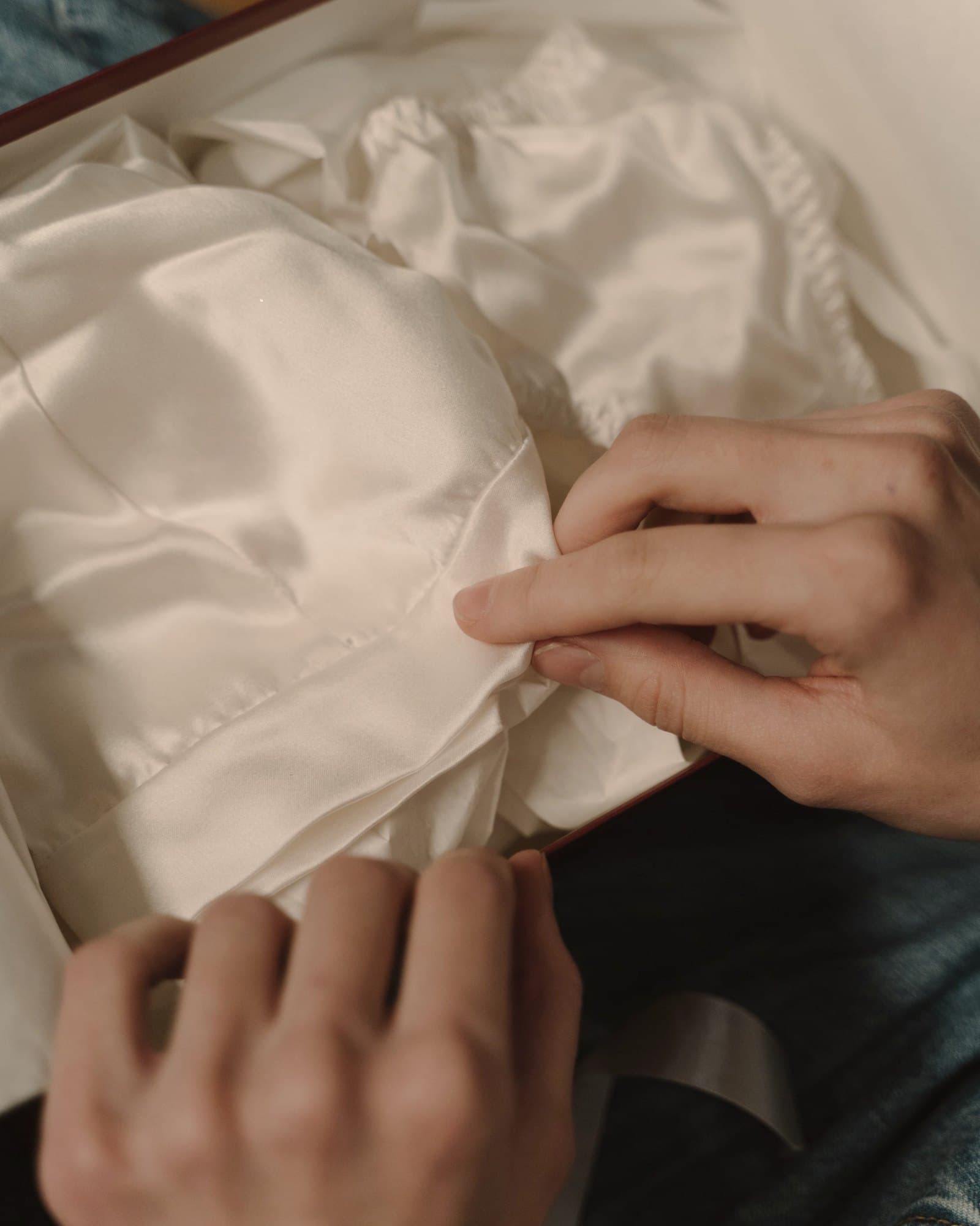 Hands folding ivory silk fabric