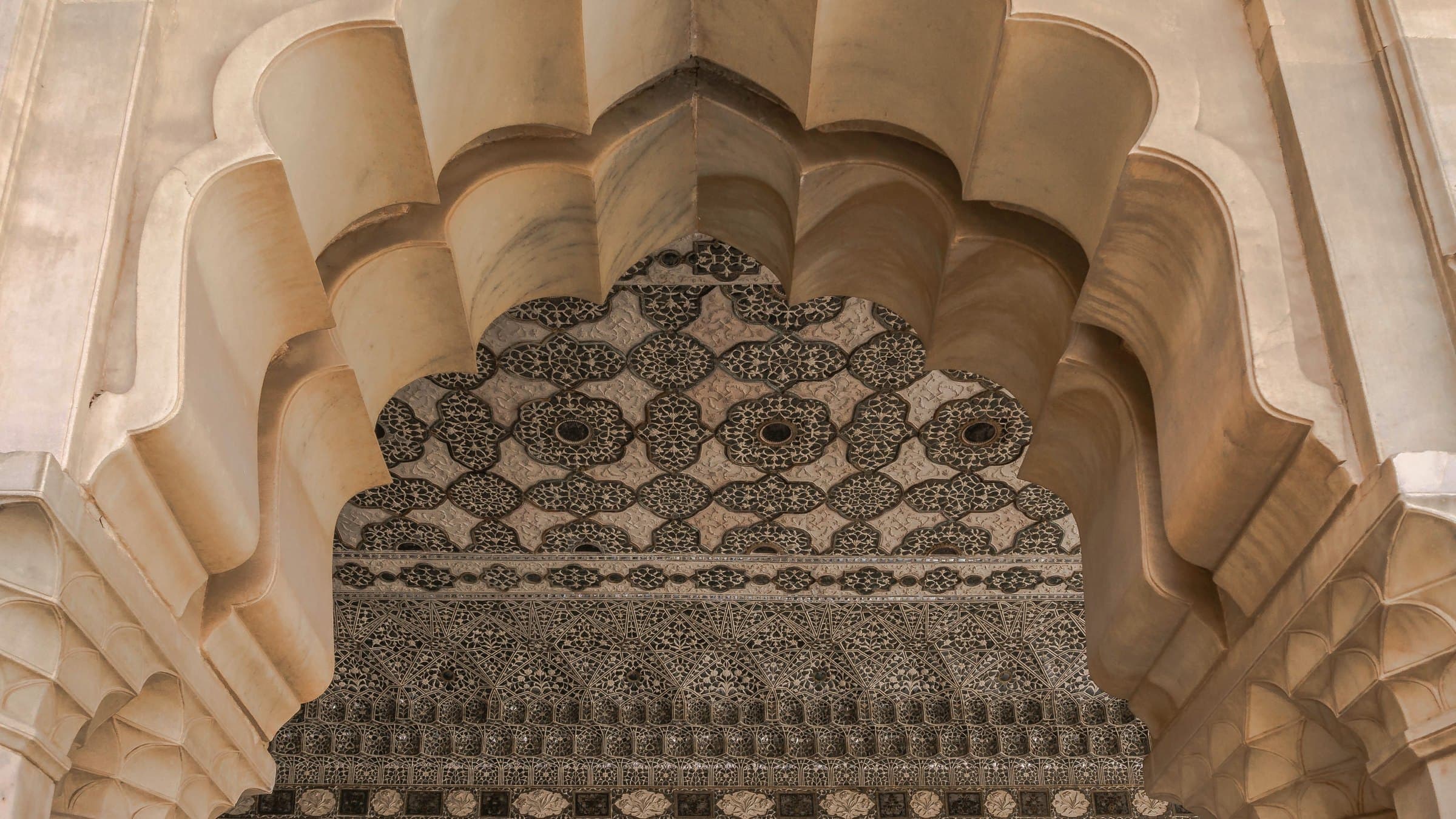 Pink sandstone facade in Jaipur with rows of carved arched windows in warm light