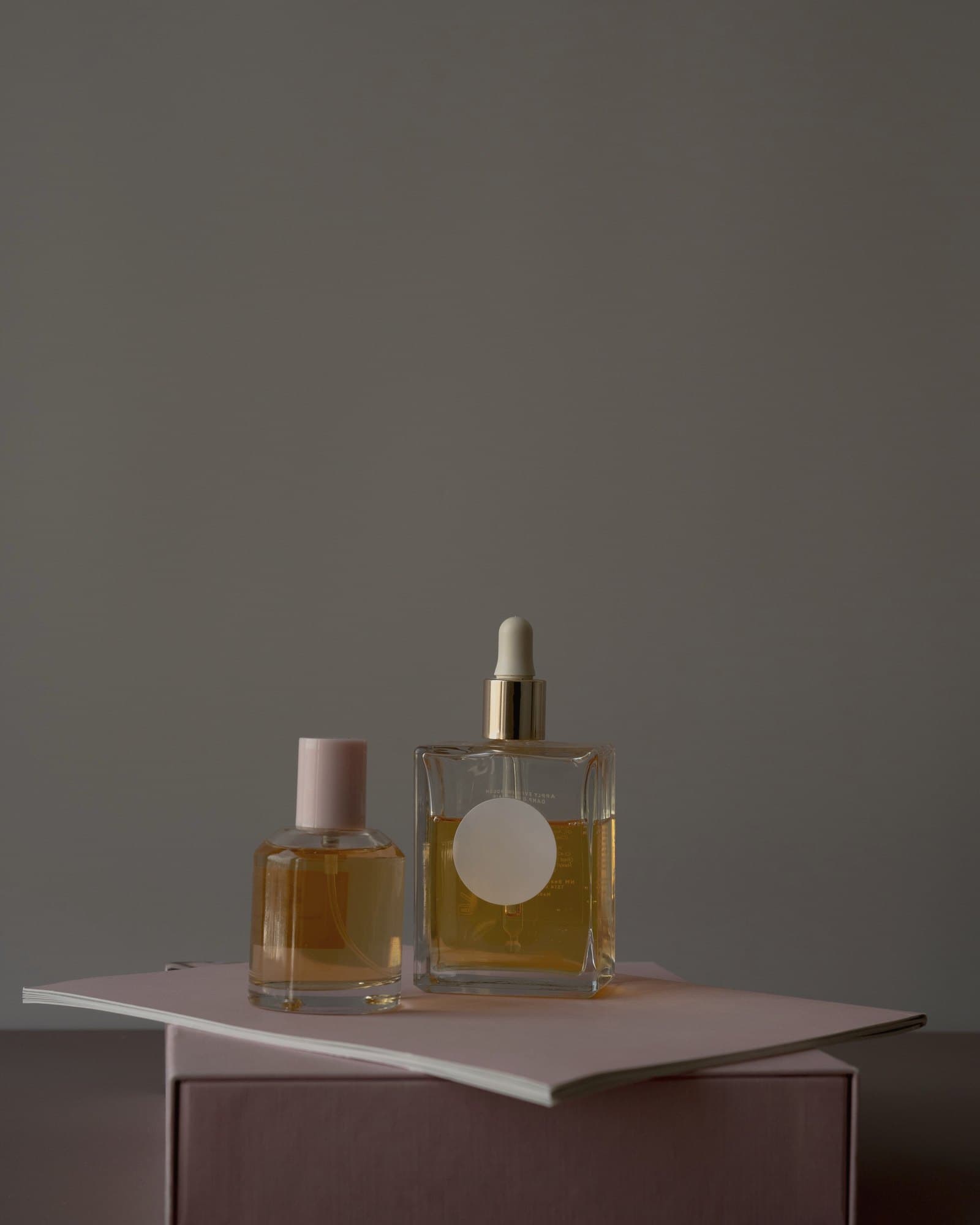 Two amber perfume bottles standing on a muted rigid box