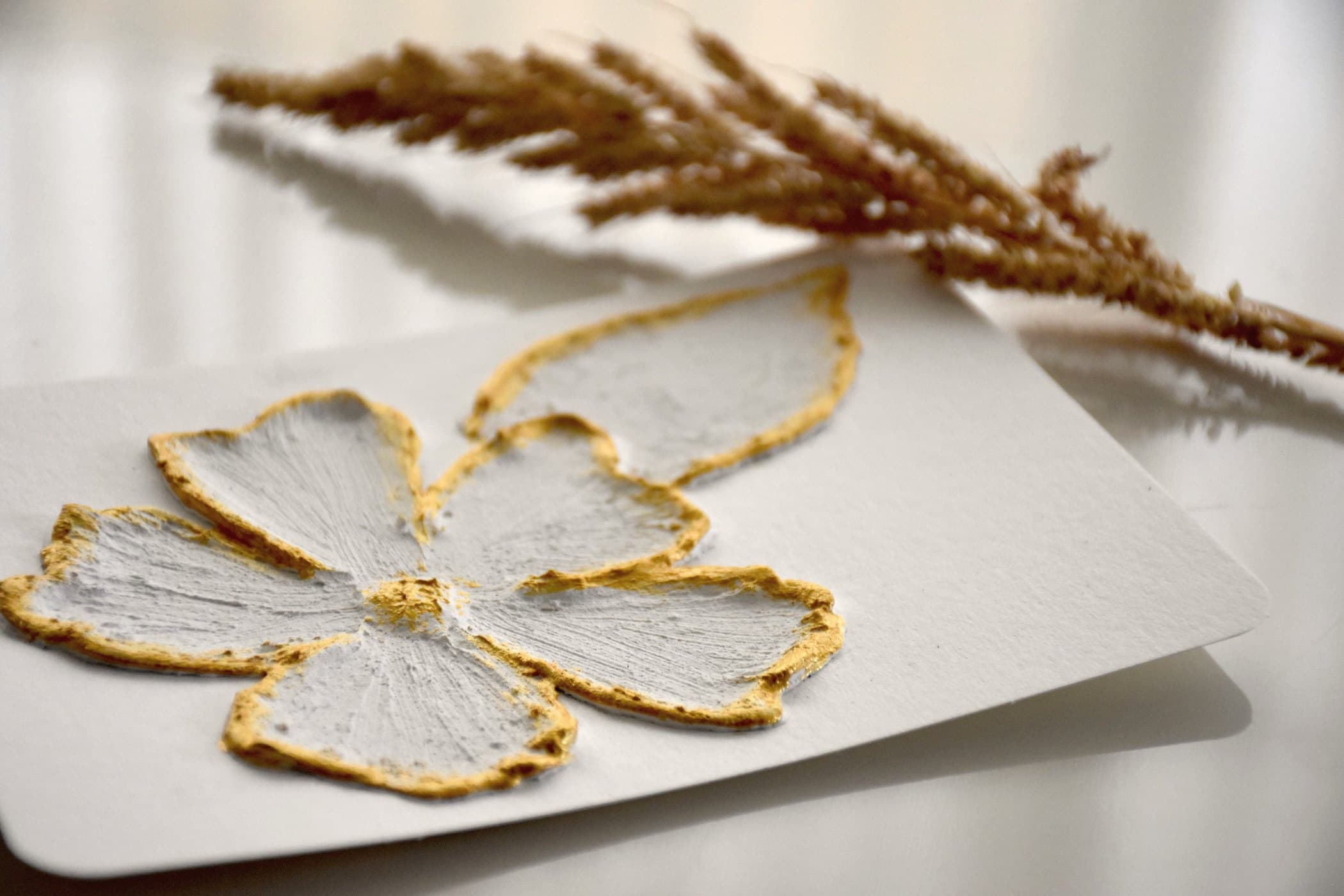Raised floral relief with gilded edges on a white card