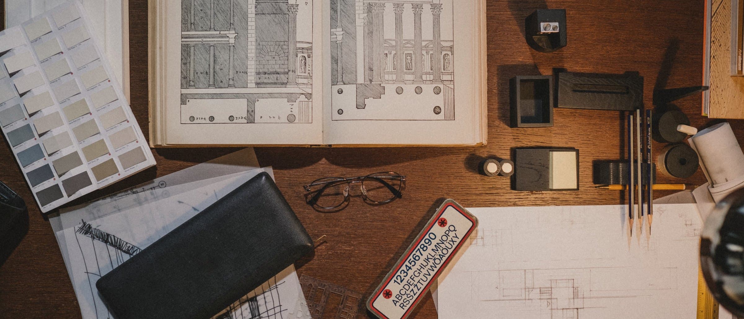 A work table with paper samples, a steel rule and pencil sketches of box layouts