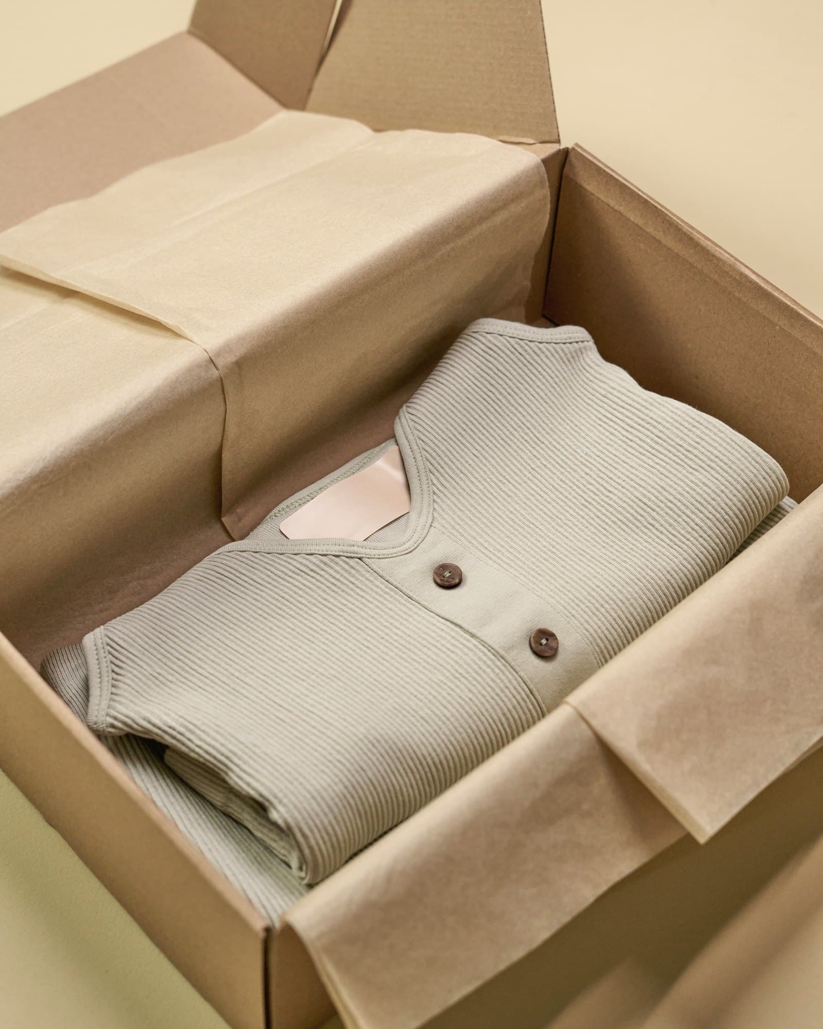 Folded knit cardigan in a kraft mailer box lined with tissue